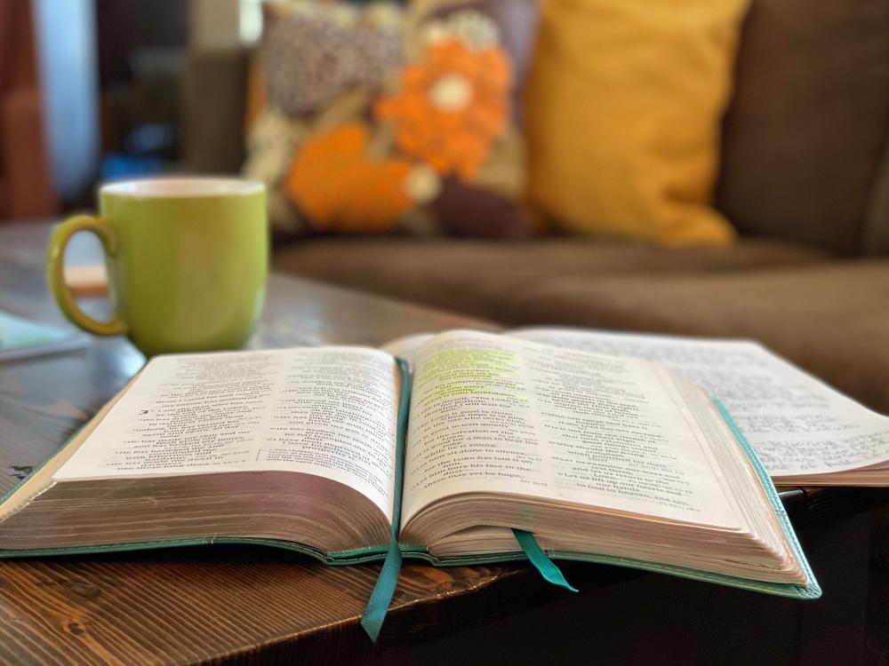 Raamattu ja kahvikuppi pöydällä. 